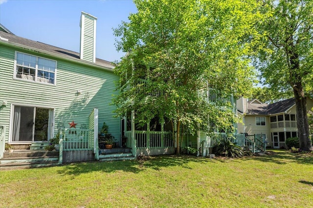 back of property with a lawn and a chimney