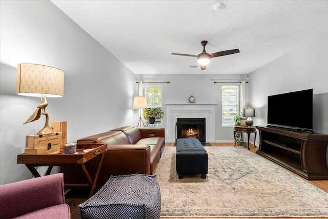 living room with a fireplace with flush hearth, wood finished floors, and ceiling fan