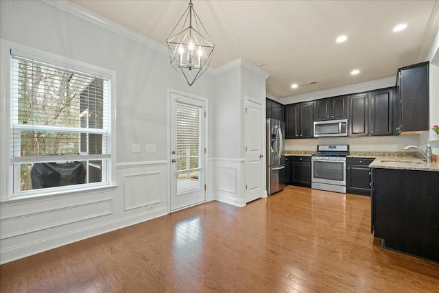 kitchen featuring sink, crown molding, pendant lighting, stainless steel appliances, and light hardwood / wood-style floors