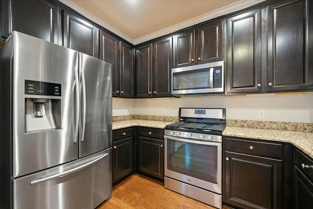 kitchen featuring light stone countertops, dark brown cabinets, stainless steel appliances, and light wood-type flooring