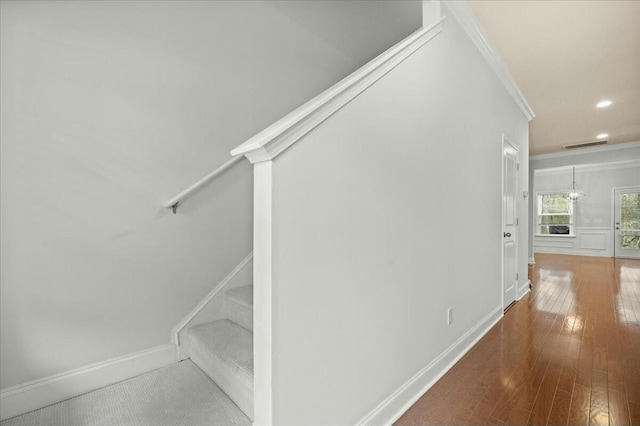 staircase featuring wood-type flooring and ornamental molding