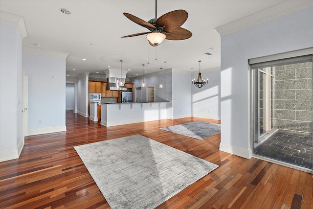 unfurnished living room featuring ornamental molding, ceiling fan with notable chandelier, and dark wood-type flooring