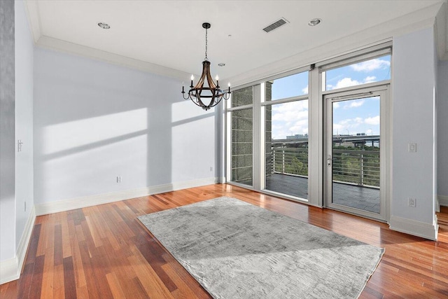 unfurnished dining area with hardwood / wood-style floors, an inviting chandelier, and ornamental molding