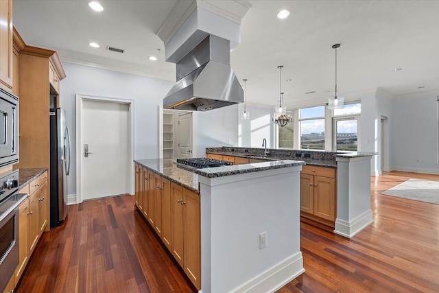 kitchen with dark stone counters, dark hardwood / wood-style floors, a kitchen island, island range hood, and stainless steel appliances