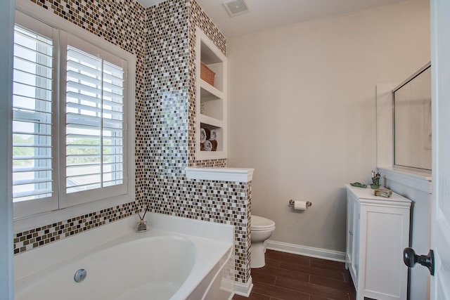 bathroom featuring a bath, toilet, wood finished floors, and baseboards