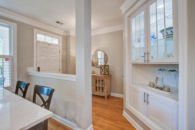 dining room with ornamental molding, baseboards, and light wood-style flooring