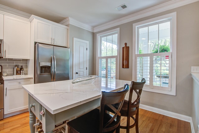 kitchen featuring stainless steel appliances, white cabinets, tasteful backsplash, light wood finished floors, and crown molding