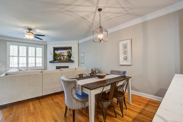 dining area featuring ornamental molding, light wood finished floors, baseboards, a ceiling fan, and a chandelier
