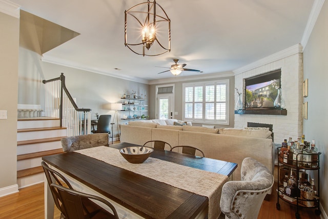 dining room with ceiling fan, light wood-style flooring, crown molding, a chandelier, and stairs