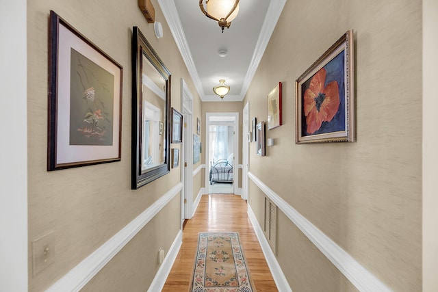 hallway featuring ornamental molding and light wood-style floors