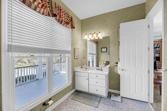 bathroom with wallpapered walls, vanity, and baseboards