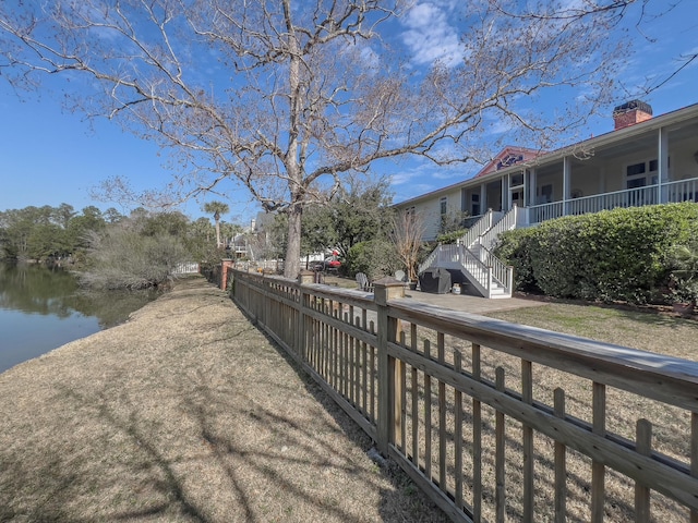 view of home's community with a water view and fence