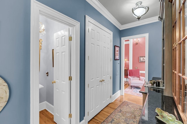 foyer with light wood-type flooring, crown molding, and baseboards