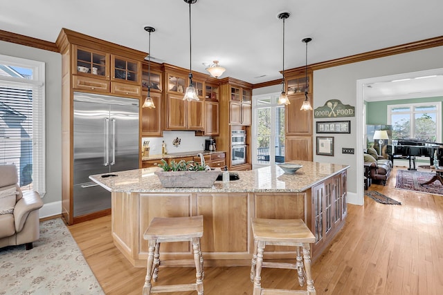 kitchen featuring open floor plan, appliances with stainless steel finishes, light wood-type flooring, and a sink