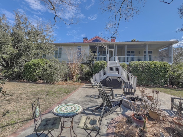 rear view of property with an outdoor fire pit, a porch, stairs, a chimney, and a patio area