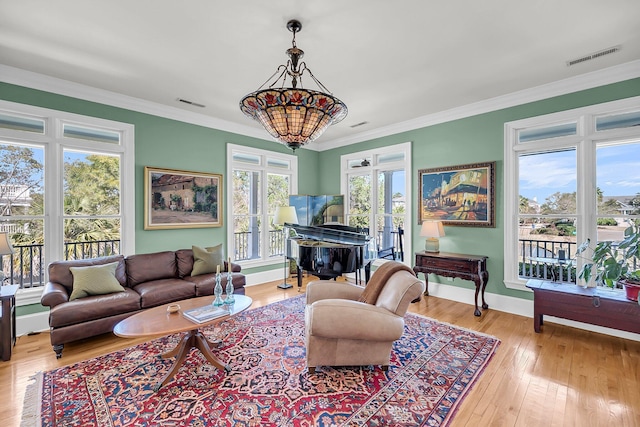 living area featuring visible vents, hardwood / wood-style floors, and ornamental molding