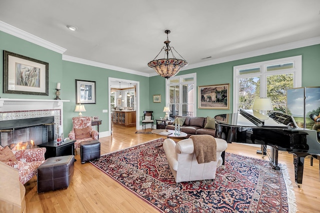 living area with wood finished floors, a tile fireplace, visible vents, and crown molding