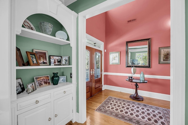 interior space with light wood finished floors, baseboards, and visible vents