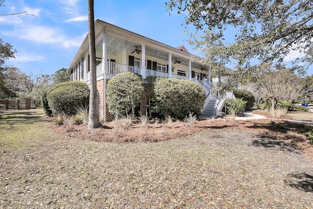 view of side of property featuring a porch, ceiling fan, and stairway