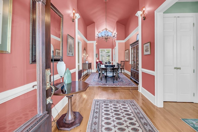 interior space with high vaulted ceiling, baseboards, an inviting chandelier, and wood finished floors