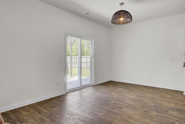 empty room with visible vents, dark wood-style flooring, and baseboards