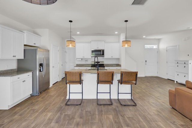 kitchen with stainless steel appliances, visible vents, a kitchen breakfast bar, and recessed lighting
