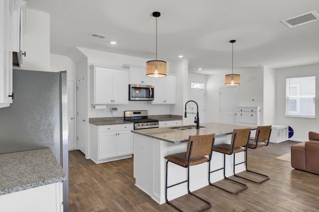 kitchen with visible vents, a sink, a kitchen breakfast bar, and stainless steel appliances