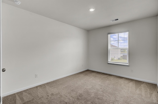 carpeted spare room with visible vents and baseboards