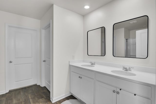 bathroom with double vanity, baseboards, a sink, and wood finished floors