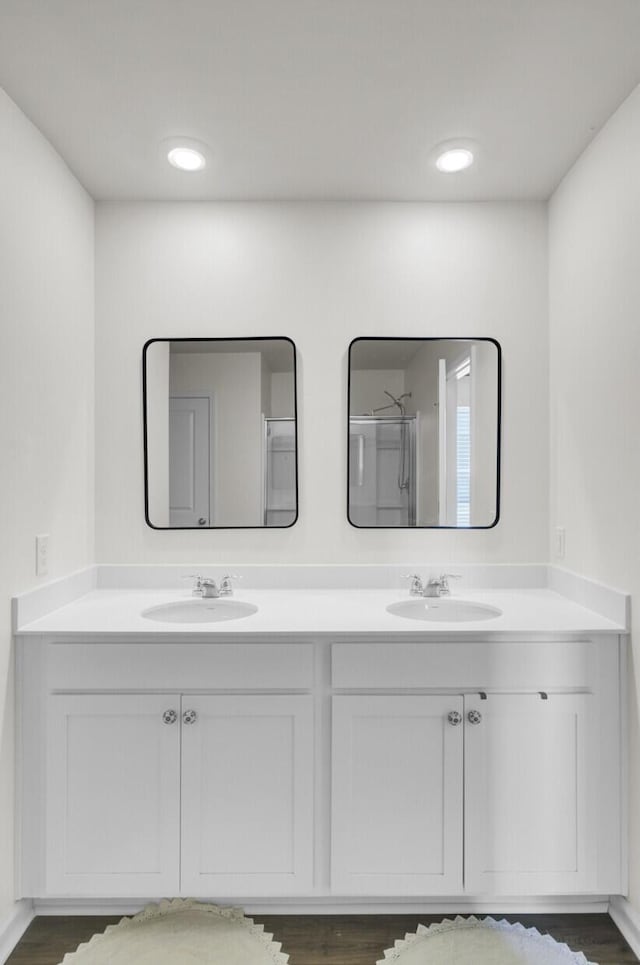 full bath featuring double vanity, a sink, and wood finished floors