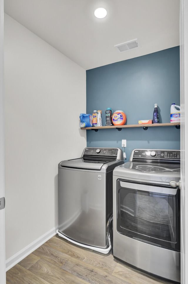 washroom with washer and dryer, laundry area, baseboards, wood finished floors, and visible vents