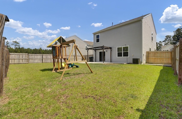 back of house with a yard, central AC, a fenced backyard, and a playground