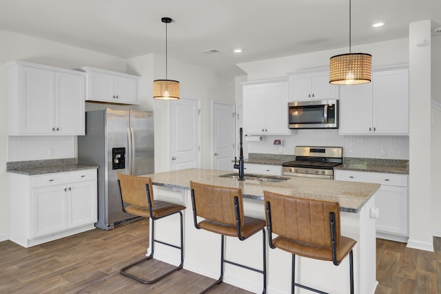 kitchen with stainless steel appliances, light stone counters, dark wood-style floors, and tasteful backsplash