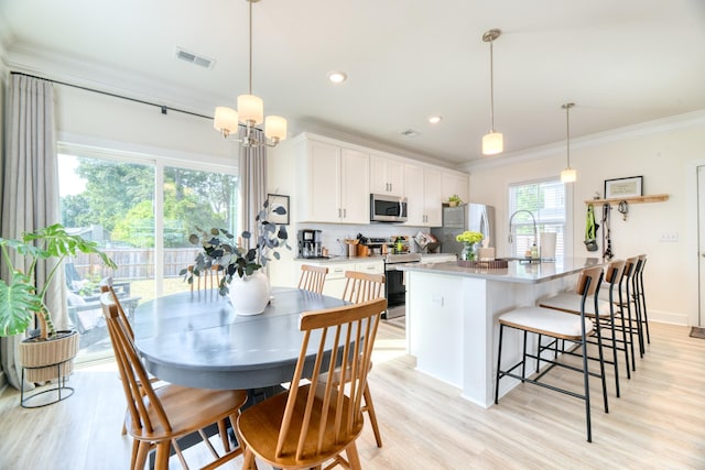 kitchen featuring light wood-type flooring, visible vents, appliances with stainless steel finishes, tasteful backsplash, and ornamental molding