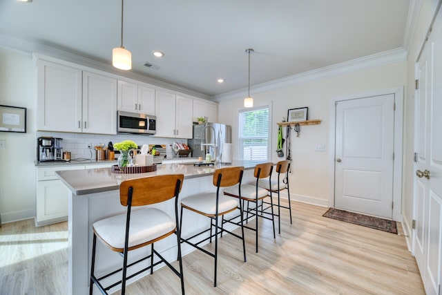 kitchen featuring an island with sink, stainless steel appliances, tasteful backsplash, and crown molding