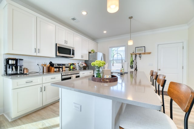 kitchen with light wood-style floors, ornamental molding, visible vents, and appliances with stainless steel finishes