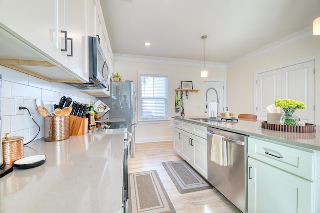 kitchen with light wood-style flooring, tasteful backsplash, a sink, white cabinets, and appliances with stainless steel finishes