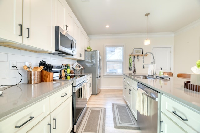 kitchen featuring a sink, stainless steel appliances, tasteful backsplash, crown molding, and light wood-style flooring