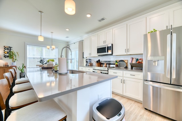 kitchen featuring a sink, stainless steel appliances, a breakfast bar, ornamental molding, and visible vents