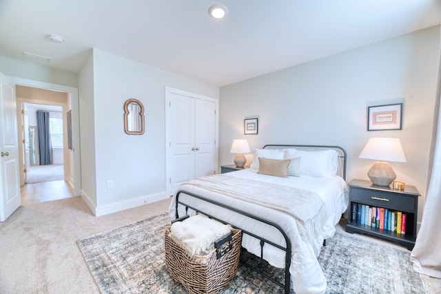 bedroom featuring baseboards, light carpet, and a closet