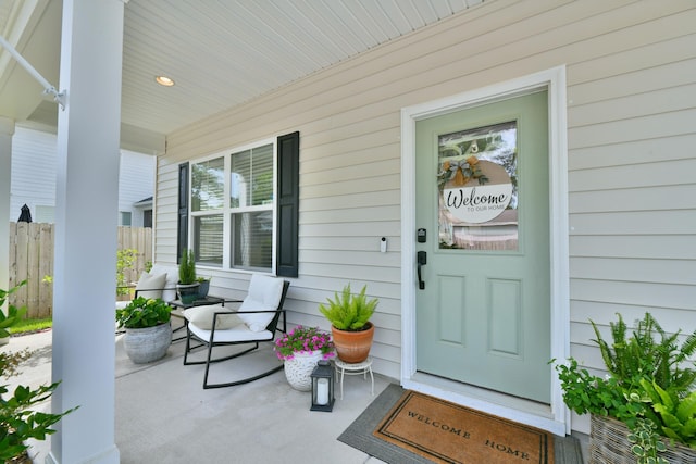 doorway to property featuring covered porch and fence
