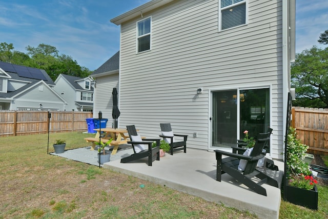rear view of property featuring a patio, a lawn, and a fenced backyard