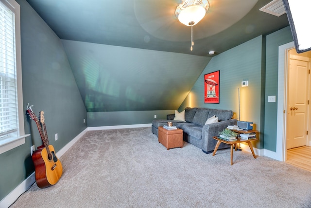 carpeted living area with lofted ceiling, baseboards, a healthy amount of sunlight, and visible vents