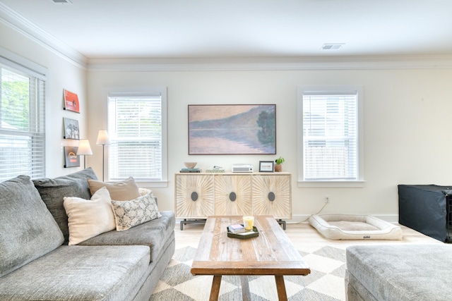 living area with ornamental molding, a healthy amount of sunlight, visible vents, and wood finished floors