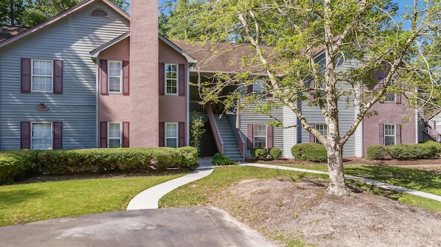 7945 Parklane Ct Unit C, North Charleston, SC 29418 - view of front facade featuring a chimney, stairway, a front lawn, and stucco siding