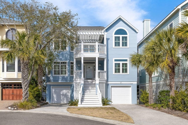 coastal inspired home with a garage, a balcony, stairs, and a pergola