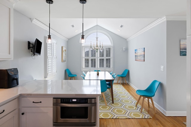 kitchen with crown molding, light wood finished floors, lofted ceiling, white cabinets, and oven