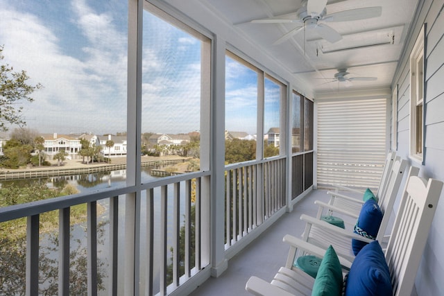 sunroom / solarium featuring a water view, a residential view, and a ceiling fan