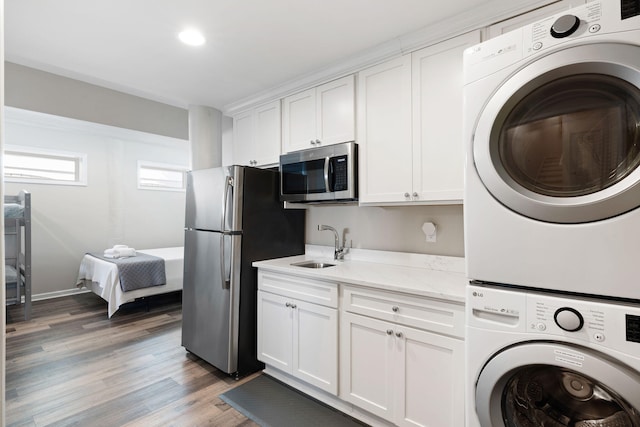 clothes washing area featuring stacked washer and dryer, light wood-style floors, laundry area, and a sink