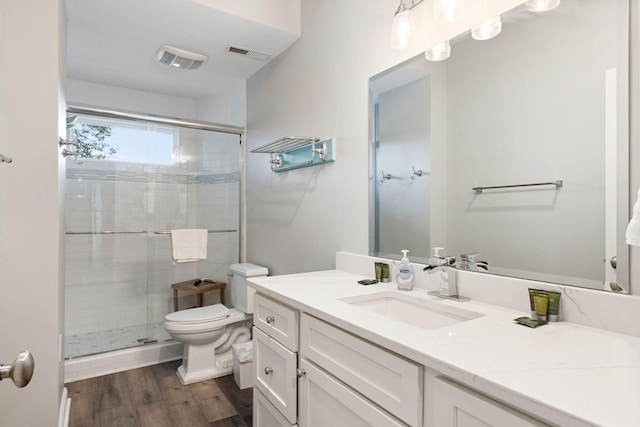 bathroom featuring a stall shower, visible vents, toilet, and wood finished floors